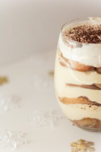 Close-up of a creamy tiramisu dessert in a glass, beautifully presented with cocoa topping, perfect for tasty indulgence.