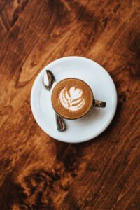 A top-down view of cappuccino with latte art, placed on a rustic wooden table.