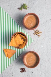 Top view of traditional Indian chai tea with nachos on a striped mat.