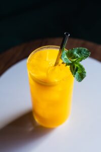 A top view of a refreshing mango juice with mint on a wooden table.